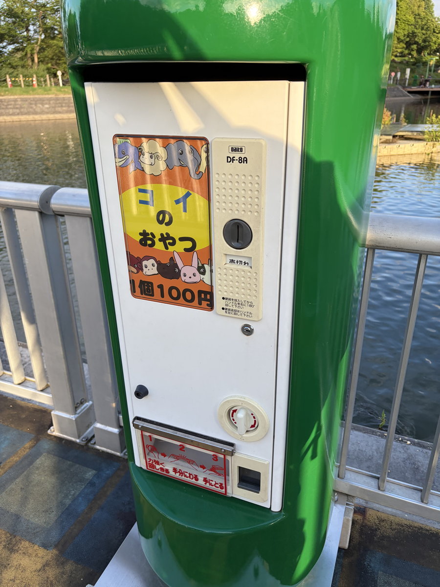 太閤山ランドの池のほとりにある「コイのおやつ」自販機(1個100円)。