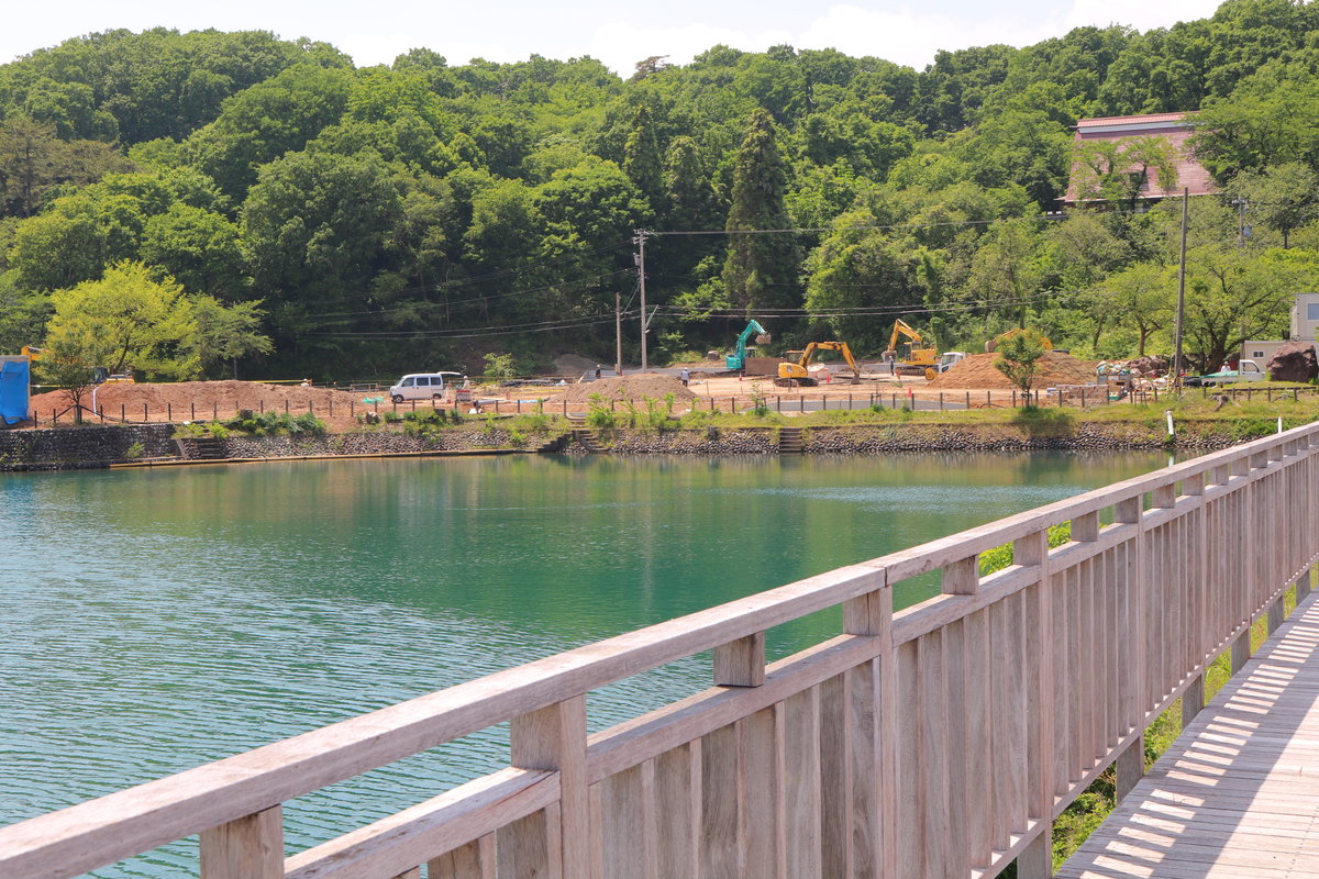 桜ヶ池のすぐほとりで重機が稼働するプレイアースパークのアクティビティセンター建設現場