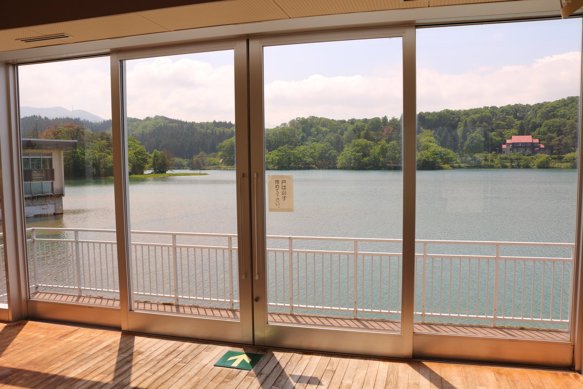 エメラルドグリーンの水面が広がる美しい桜ヶ池と背後に連なる里山の風景